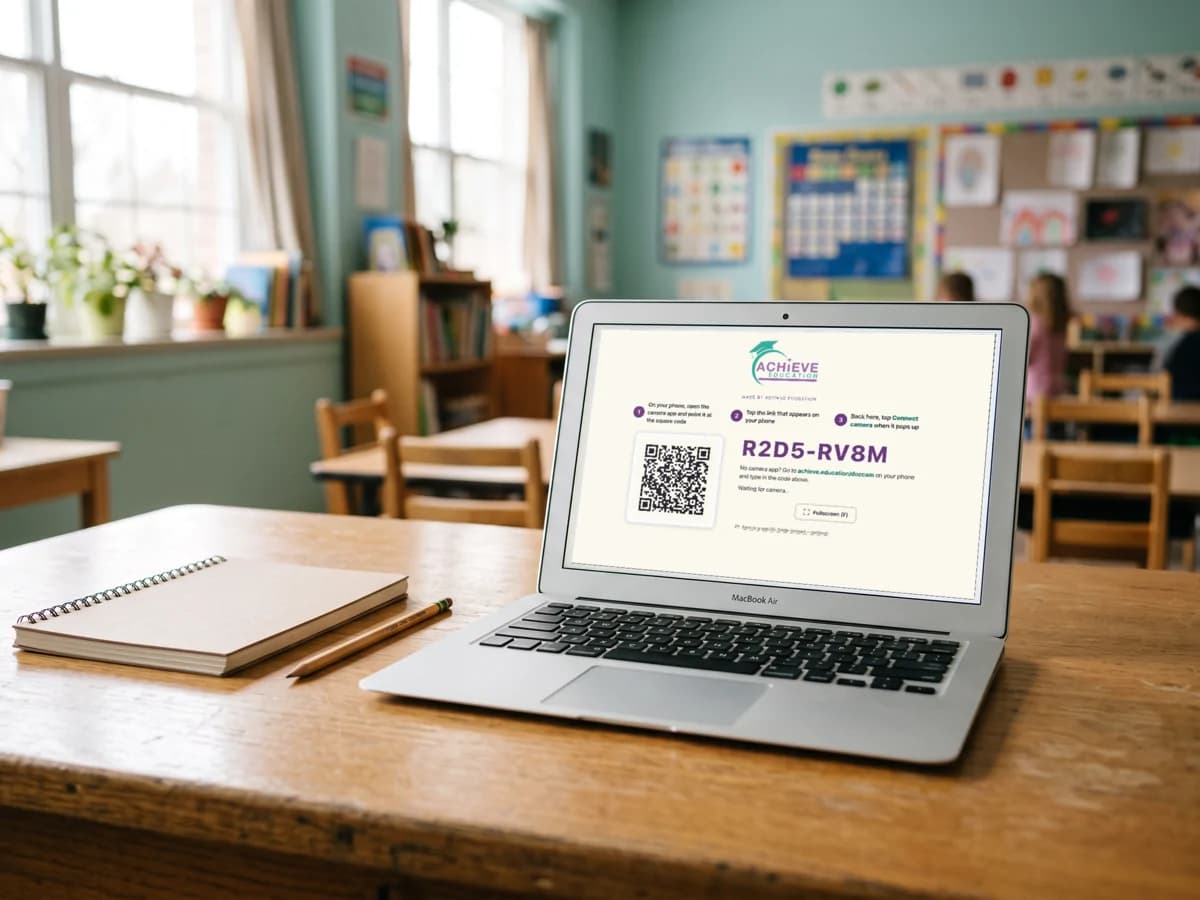 A laptop on the teacher desk showing a large QR code on the screen