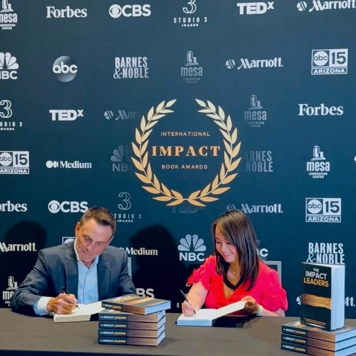Kevin Harrington and Kimly Hoang-Nakata signing books side by side at the conference