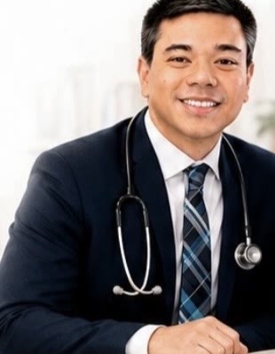 Dr. Roger Nakata, D.O., pediatrician, smiling in a navy suit with a stethoscope